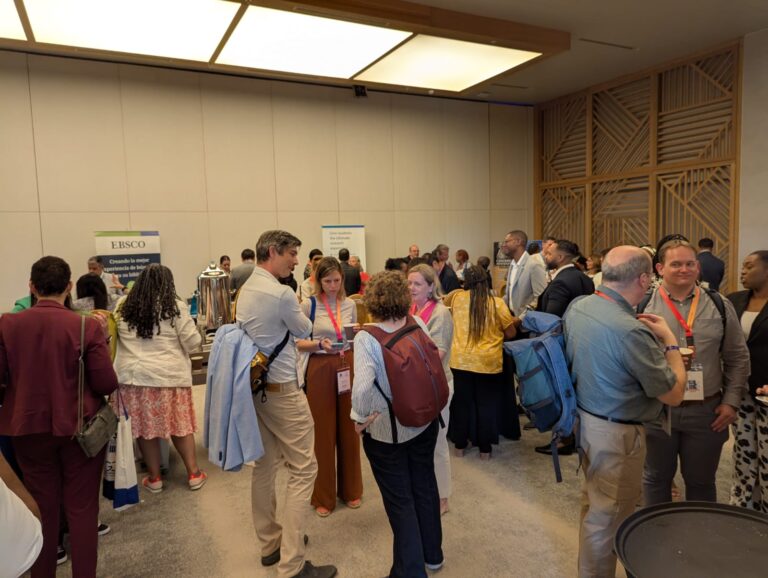 Asistentes socializando y explorando exposiciones en la conferencia ACURIL 2025