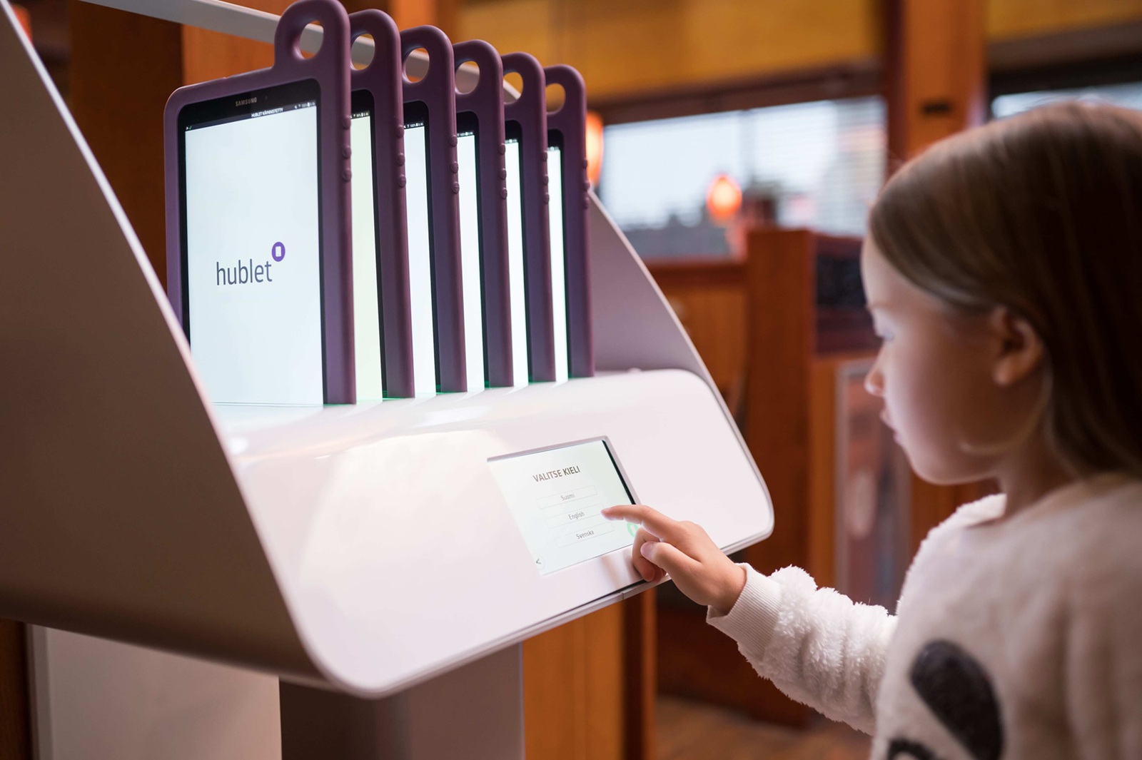 Girl interacts with a Hublet Smart Docking Station to borrow a tablet.