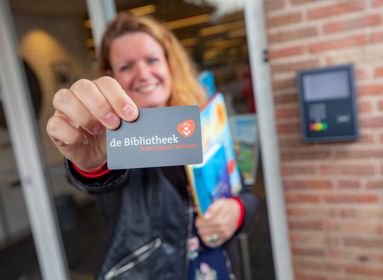 Lady holding up library card with open+ access panel behind