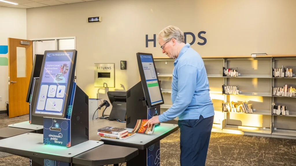A patron uses the selfCheck 3000 kiosk at Cincinnati Public Library to check out materials. The kiosk integrates Bibliotheca’s quickConnect platform with TBS’s print release tools.